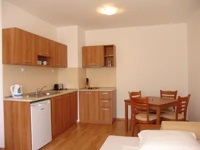 a kitchen with wooden cabinets and a table in a room at Apart Hotel Kasandra in Sunny Beach
