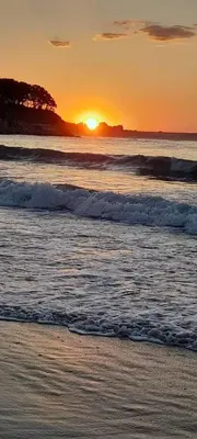 a sunset on the beach with the waves at Guest House Kostovi in Kiten
