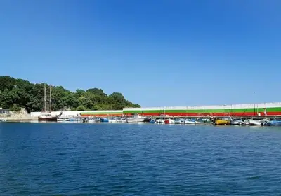 a marina with boats in the water with a train at Guest House Kostovi in Kiten
