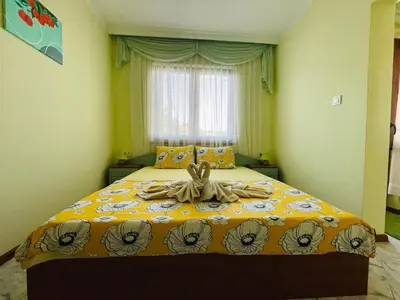 a bedroom with a large bed with a yellow comforter at Kastela Guest House in Chernomorets