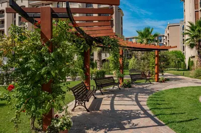 a park with benches and a wooden pergola at Menada Apartments in Cascadas in Sunny Beach