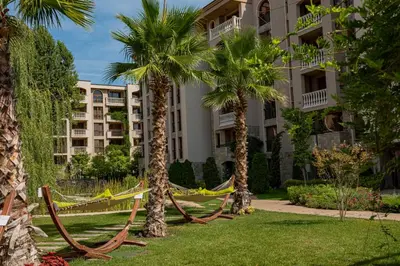 a hammock between two palm trees in front of a building at Menada Apartments in Cascadas in Sunny Beach