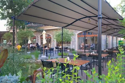 a patio with tables and chairs under an umbrella at Menada Apartments in Cascadas in Sunny Beach