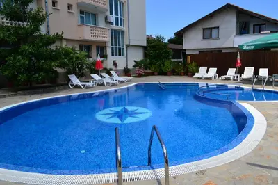 a large blue swimming pool with chairs and an umbrella at Saint George Family Hotel in Lozenets