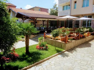 a garden in front of a building with plants and umbrellas at Saint George Family Hotel in Lozenets