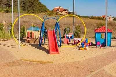 a playground with colorful play equipment in the sand at Menada Sozopol Apartments in Sozopol