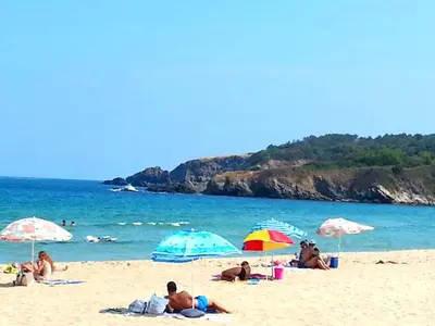 a group of people laying on a beach with umbrellas at Menada Sozopol Apartments in Sozopol
