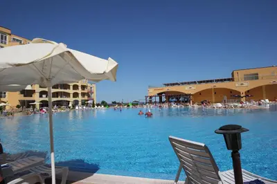 a large swimming pool with chairs and an umbrella at Menada Grand Resort Apartments in Aheloy