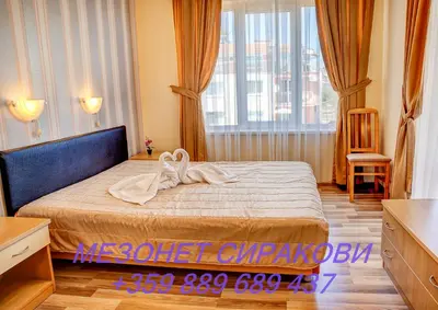a bedroom with a bed and a large window at Мезонет Сиракови in Sozopol