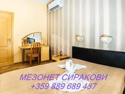 a hotel room with a bed and a desk at Мезонет Сиракови in Sozopol
