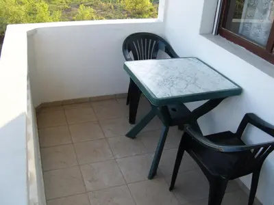 a green table and a chair in a window at Kirovi House - guest rooms in Tsarevo