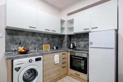 a kitchen with white cabinets and a washer and dryer at Studio Thermi 1 in Varna City
