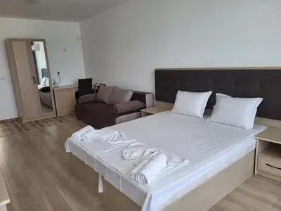 a large white bed in a room with a couch at Perla Del Mar Aparthotel in Lozenets