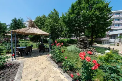 a garden with a table and a gazebo and flowers at Belitsa Hotel in Primorsko