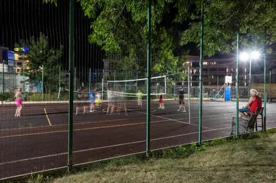 a group of children playing tennis on a tennis court at night at Belitsa Hotel in Primorsko