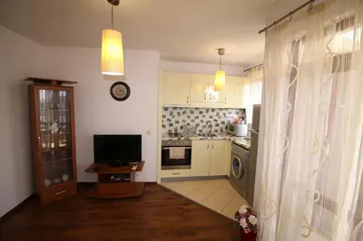 a kitchen with white cabinets and a television and a table at SEA PANORAMA appartment in Varna City