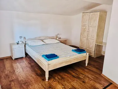 a bedroom with a bed and a wooden floor at Paunovi Guest House in Primorsko