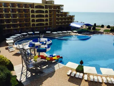 a large swimming pool with chairs and a slide in front of a hotel at PSB Apartments in Midia Resort Aheloy in Aheloy