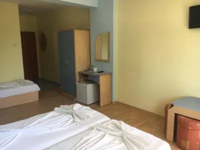 a room with two beds and a desk in it at Arkadia Guest House in Primorsko