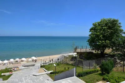a beach with tables and umbrellas and the ocean at Майстор Костадин - 1878 in Obzor