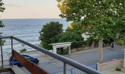 a blue car parked on a street next to the ocean at Майстор Костадин - 1878 in Obzor