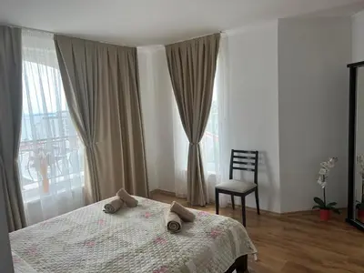 a bedroom with a bed and a chair and a window at Antorini Apartments in Sveti Vlas