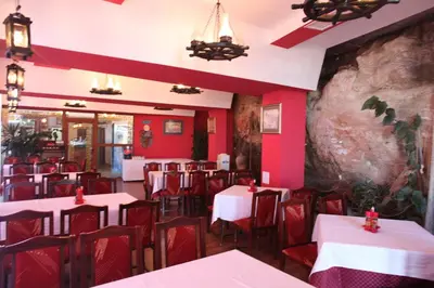 a restaurant with red walls and white tables and chairs at Ribarska Sreshta Family Hotel in Tsarevo