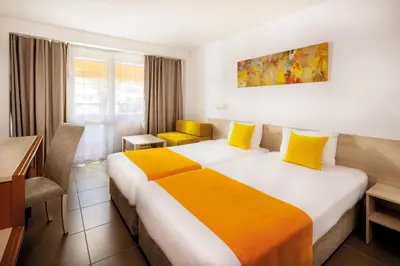 a hotel room with two beds and a desk at AluaSun Helios Beach - All Inclusive in Obzor