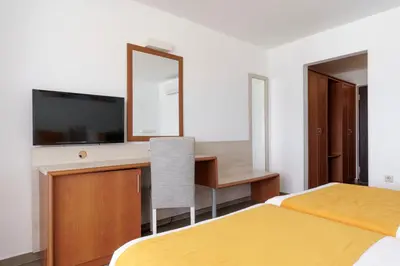 a hotel room with two beds and a desk and a mirror at AluaSun Helios Beach - All Inclusive in Obzor