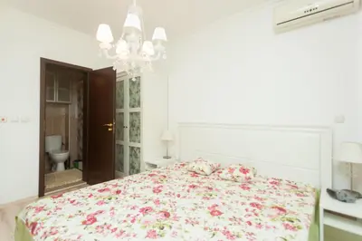 a white bedroom with a large bed with flowers at Dom-El Real Apartments Amphora in Sveti Vlas
