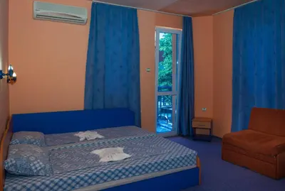 a bedroom with a bed and a chair and a window at Dara Hotel in Primorsko