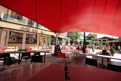 a restaurant with tables and chairs and a red umbrella at Menada Midia Apartments in Sunny Beach