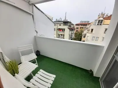 two white chairs on a balcony with green grass at Colorful 1-BDR Apartment - Top center of Burgas by Flаt Manаger in Burgas City