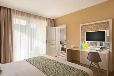 a bedroom with a bed and a desk with a television at Marina White Sands Beach Hotel-All Inclusive in Obzor