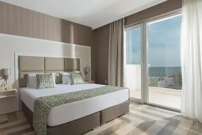 a bedroom with a large bed and a large window at Marina White Sands Beach Hotel-All Inclusive in Obzor
