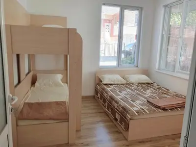 a bedroom with a bunk bed and two windows at Апартамент Катлена in Pomorie