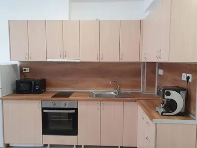 a kitchen with wooden cabinets and a sink at Апартамент Катлена in Pomorie