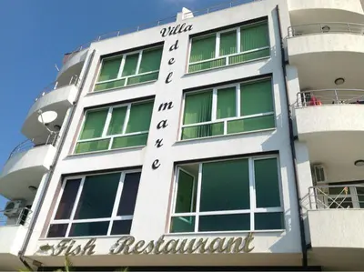 a white building with a sign on the side of it at Apartament Villa Del Mare in Primorsko