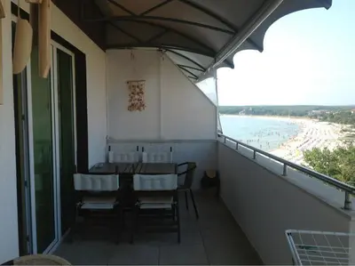 a balcony with a table and chairs and the beach at Apartament Villa Del Mare in Primorsko