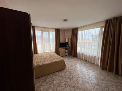 a bedroom with a bed and two large windows at Stamatovi Family Hotel in Pomorie