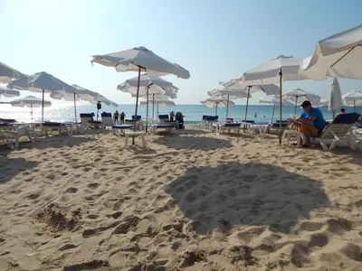 a beach with umbrellas and people sitting on the sand at Dunav Apt.2 in Ravda