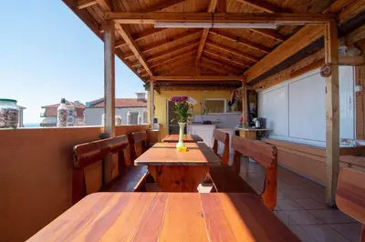a patio with wooden tables and chairs and a kitchen at Fener Guest House in Pomorie