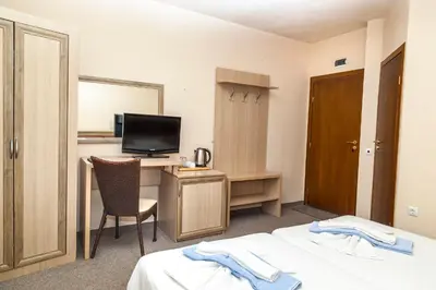 a hotel room with a bed and a desk with a television at Ravda Bay Guest House in Ravda