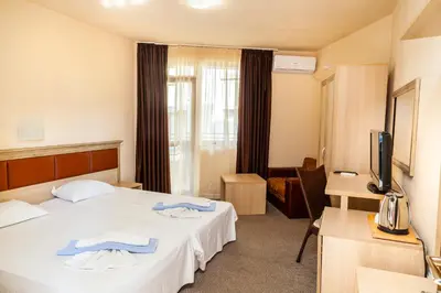 a hotel room with a bed and a television at Ravda Bay Guest House in Ravda