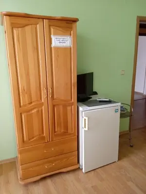 a wooden cabinet next to a small refrigerator and a television at Къща за гости Ганчеви in Sozopol