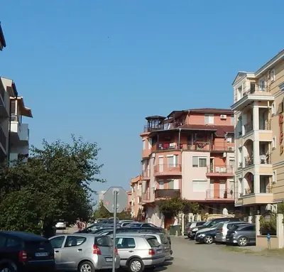 a parking lot with cars parked in front of a building at Dunav Apt.3 in Ravda