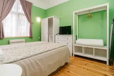 a bedroom with green walls and a bed and a television at Апартамент ELSOR in Burgas City