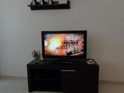 a flat screen tv sitting on top of a black entertainment center at Zoya Apartment in Burgas City