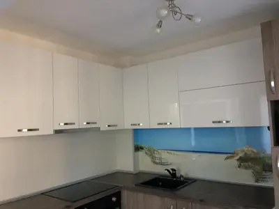 a kitchen with white cabinets and a fishtank at Апартамент Мони in Burgas City