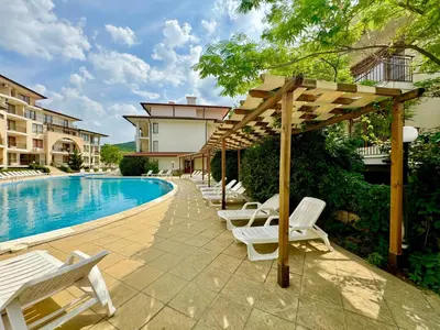 a row of white lounge chairs next to a swimming pool at Arkite Complex in Sunny Beach